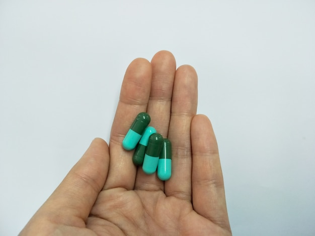 Photo pilules de médecine, comprimés et gélules à la main les femmes sur fond blanc