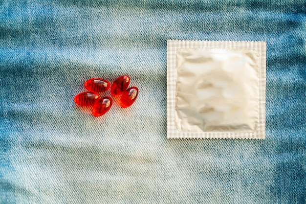 Pilules de médecine et préservatif dans un jean de poche.