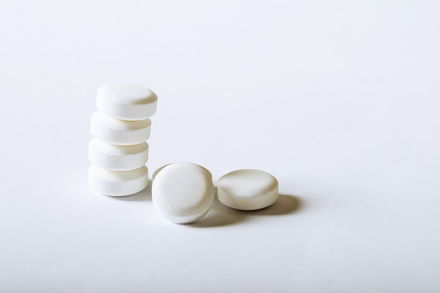 Pilules de pharmacie blanches sur fond blanc.