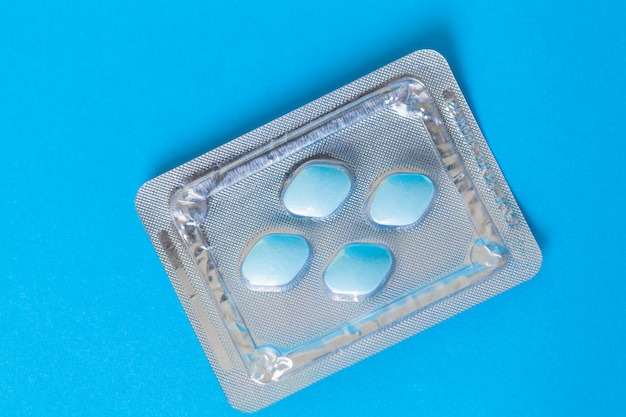 Pilules pour la santé sexuelle masculine sur une surface bleue