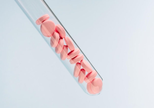 Pilules de rose dans le tube à essai sur fond bleu Espace de copie pour textxAMedicine recherchant des antécédents pharmaceutiques