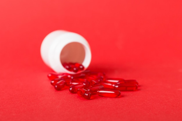 Pilules rouges renversées autour d'une bouteille de pilules Médicaments et pilules sur ordonnance fond plat Capsules médicales rouges