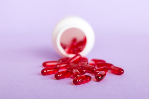 Pilules rouges renversées autour d'une bouteille de pilules Médicaments et pilules sur ordonnance fond plat Capsules médicales rouges