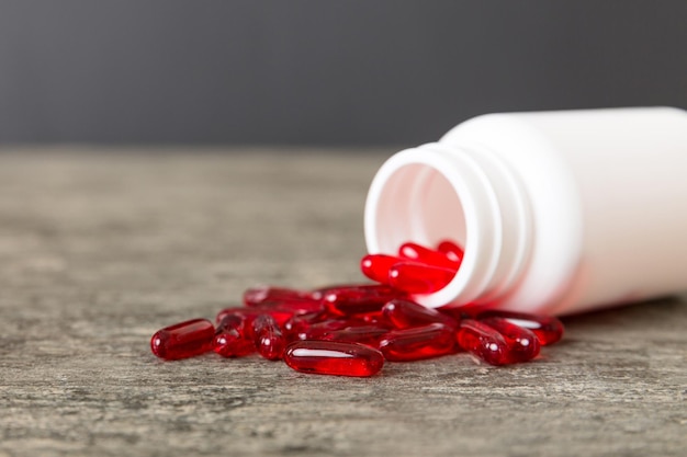 Pilules rouges renversées autour d'une bouteille de pilules Médicaments et pilules sur ordonnance fond plat Capsules médicales rouges