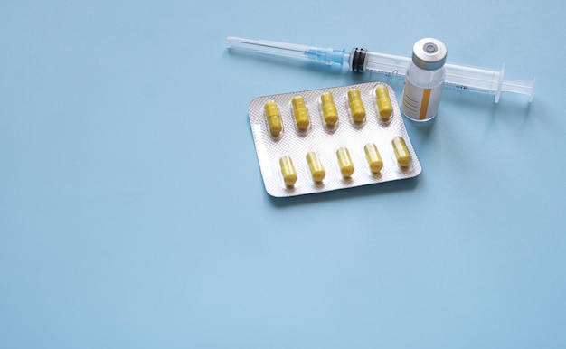 Pilules de seringue et vaccin sur fond bleu avec espace de copie