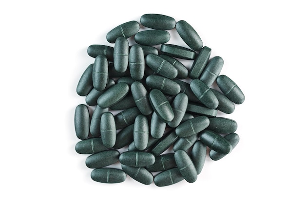 Pilules avec vitamines et spiruline sur fond blanc. Supplément sportif