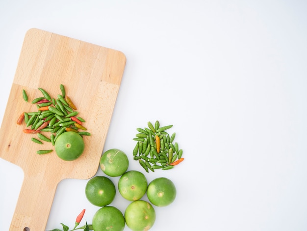 Piment et citron vert sur une planche à découper en bois.