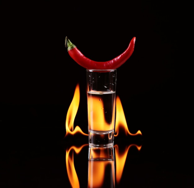 Piment fort dans un verre à liqueur avec un feu sur noir