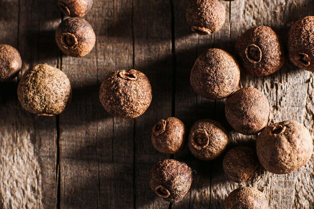 Piment de la Jamaïque versé sur une table en bois Pile de grains de poivre sur fond de texture