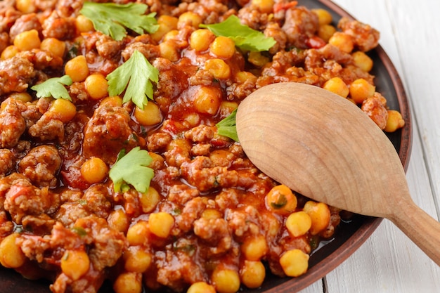 Piment mexicain avec pois chiches bi et cuillère en bois sur une table en bois