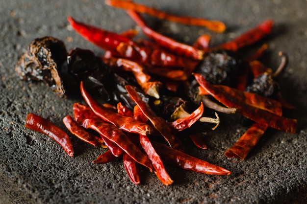 Piment mexicain séché, y compris des variétés de piment ancho et de piment arbol sur un fond de métate traditionnel