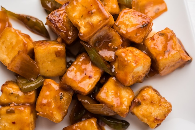 Piment paneer ou fromage cottage épicé, servi dans un plat blanc avec poivron et oignon, menu de démarrage indien préféré, mise au point sélective