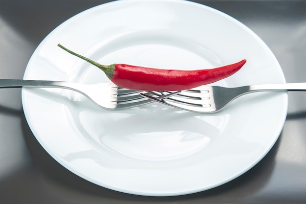 Piment rouge avec fourchette gros plan sur assiette.