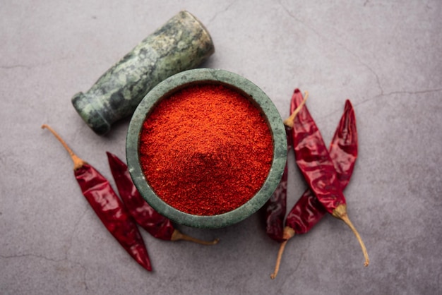 Piment rouge ou Lal Mirchi ou mirch avec de la poudre dans un bol ou un mortier sur fond de mauvaise humeur, mise au point sélective