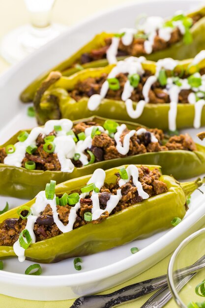 Piments chili farcis au bœuf chipotle et aux haricots garnis de crème sure et d'oignons verts.