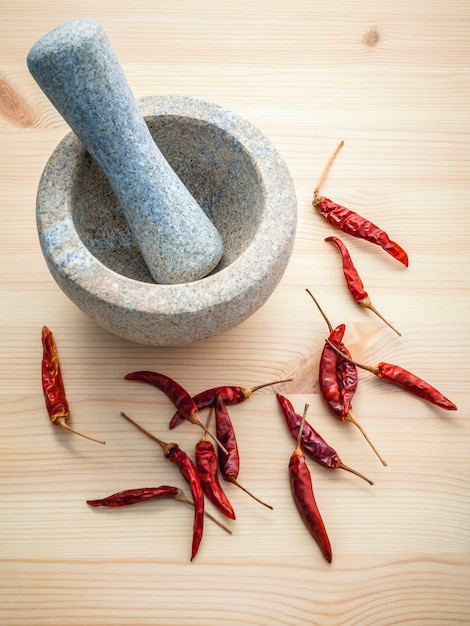 Piments sur fond en bois blanc avec mortier et pilon.