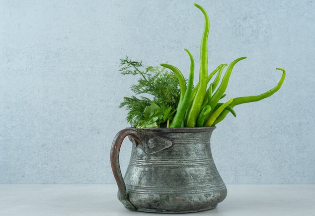 Piments forts et verts dans un plat en fer, sur le marbre.