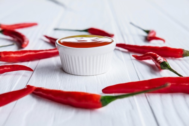 Photo piments frais avec sauce chili piquante sur fond blanc