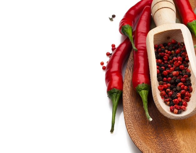 Piments et grains de poivre dans une cuillère en bois