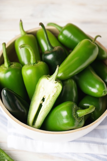 Piments jalapenos verts dans une assiette en bois sur un fond en bois. Fermer.