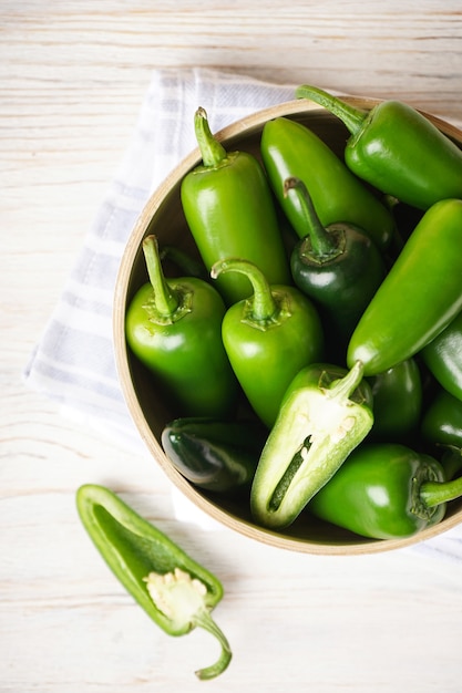 Piments jalapenos verts dans une assiette en bois sur un fond en bois. Vue de dessus.