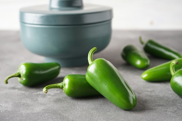 Piments jalapenos verts dans un bol en céramique sur fond gris. Fermer.