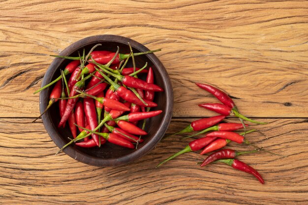 Piments malagueta rouges sur un bol au-dessus d'une table en bois.