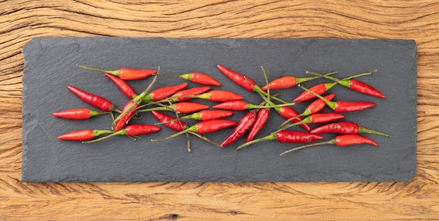 Piments malagueta rouges sur une planche en pierre sur une table en bois.