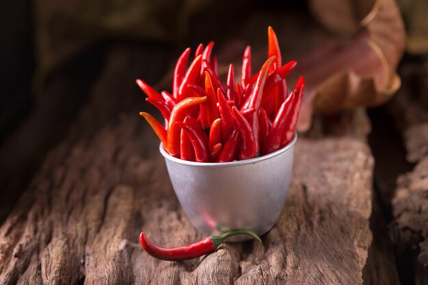 Piments rouges dans un bol de zinc sur fond en bois