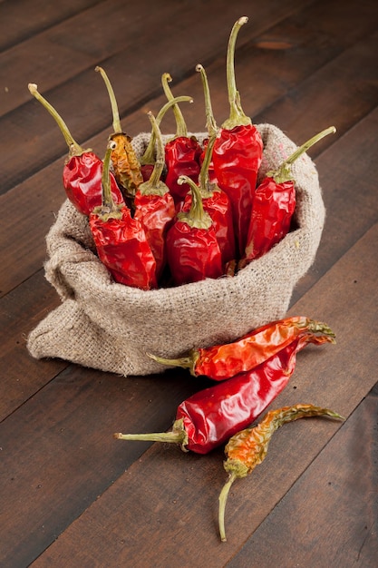 Piments rouges dans un sac en toile sur une table en bois