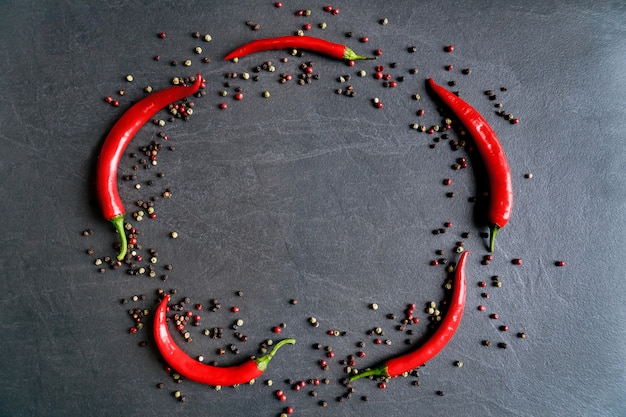 Piments rouges sur fond gris foncé avec du poivre