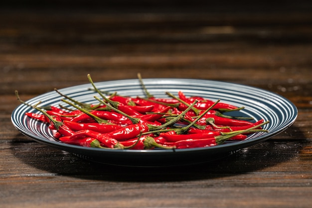 Piments rouges frais dans une assiette sur une table en bois