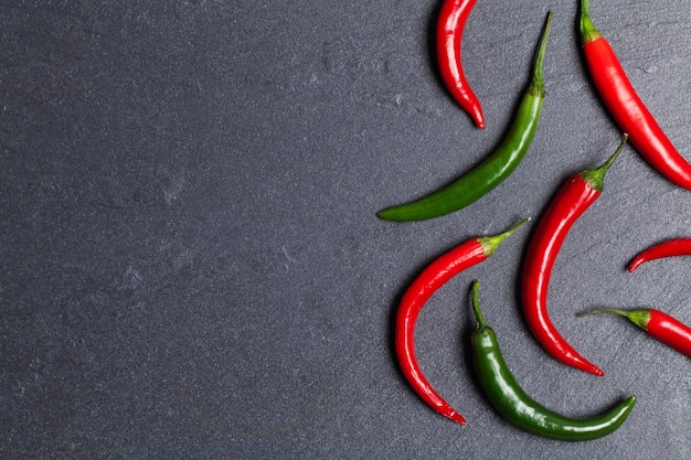 Piments rouges frais avec un vert sur un fond d'ardoise sombre