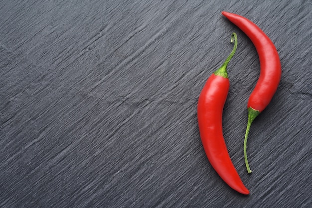 Piments rouges sur mur d'ardoise noir foncé avec espace copie. Vue de dessus