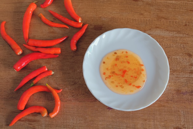 Piments rouges et sauce chili en plat sur table en bois