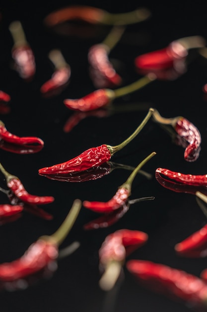 Photo piments secs allongés sur une surface miroir noire