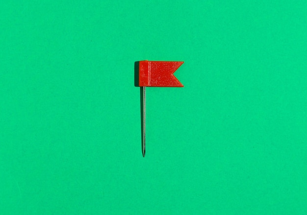 Photo pin's petit drapeau rouge sur fond vert. vue d'en-haut .