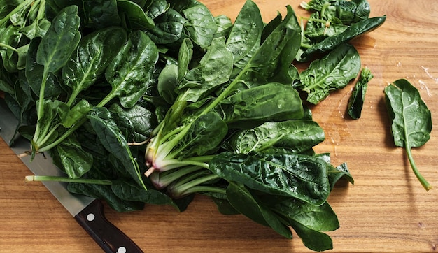 Épinards, feuilles d'épinards frais et juteux sur une planche à découper en bois. Alimentation biologique et saine. Vue de dessus, idée de faire de la salade pour le petit déjeuner