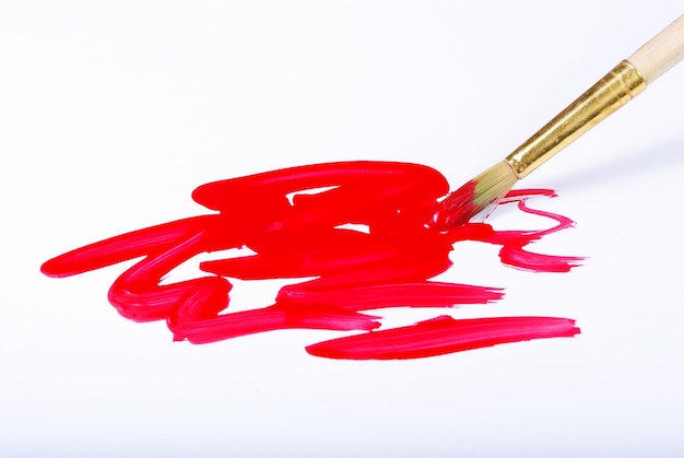 Pinceau d'artiste et coups de pinceau rouges sur blanc