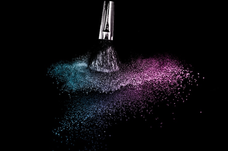 Photo pinceau cosmétique avec poudre cosmétique pourpre et bleu de la mer se répandant pour maquilleuse ou graphiste sur fond noir