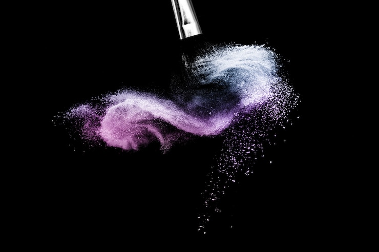 Photo pinceau cosmétique avec poudre cosmétique violette et bleue étalée pour maquilleuse ou graphiste en fond noir