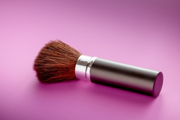 Pinceau de maquillage sur fond de texture de papier rose pastel