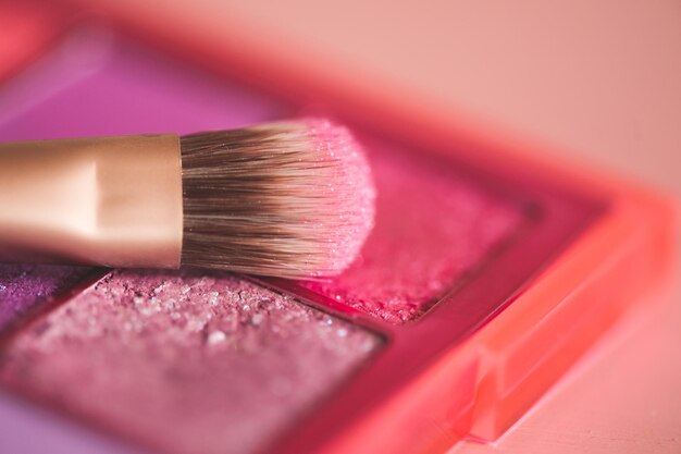 Pinceau de maquillage sur les ombres roses pailletées se bouchent. Mise au point sélective.