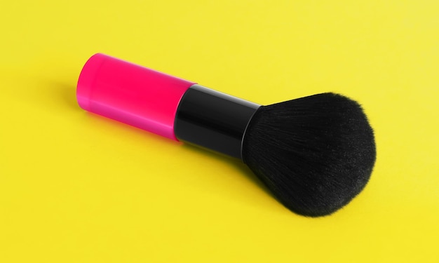 Un pinceau de maquillage rose sur fond jaune