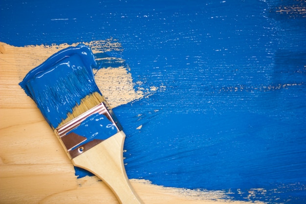 Photo pinceau en peinture bleue sur une planche de bois