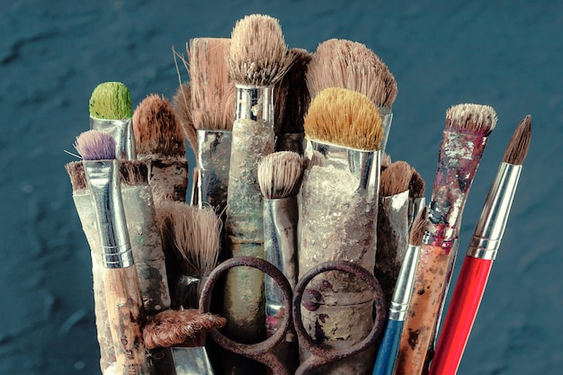 Photo des pinceaux d'art ancien se tiennent sur le mur bleu d'un mur de couleur dans l'atelier de l'artiste