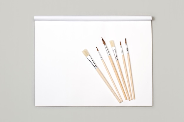 Pinceaux artistiques en bois sur un bloc de papier blanc avec espace de copie