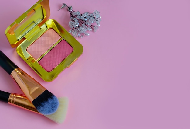 Pinceaux de maquillage haut de gamme dans un sac cosmétique, palette de fard à joues sur fond rose coloré