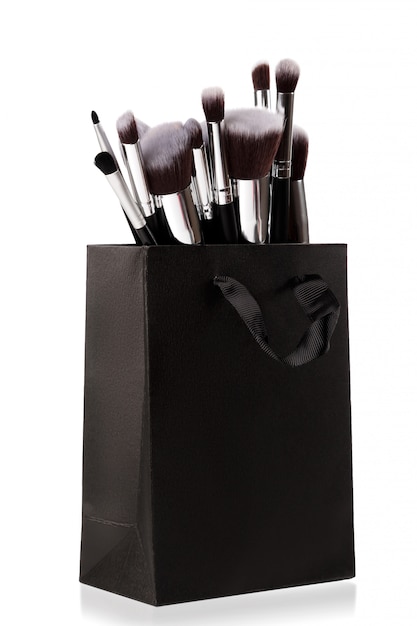 Pinceaux de maquillage professionnels dans un sac à provisions noir