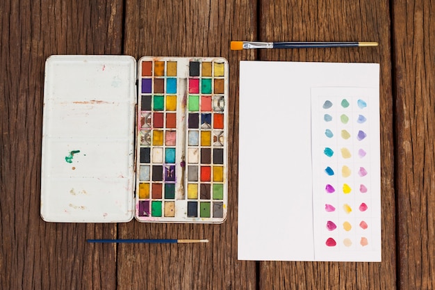 Photo pinceaux, palette et papier blanc sur table en bois